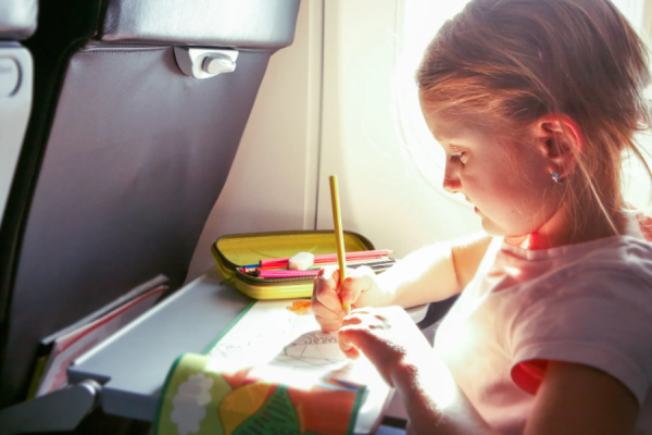 Young child doing colors on her colouring book while on a plane.