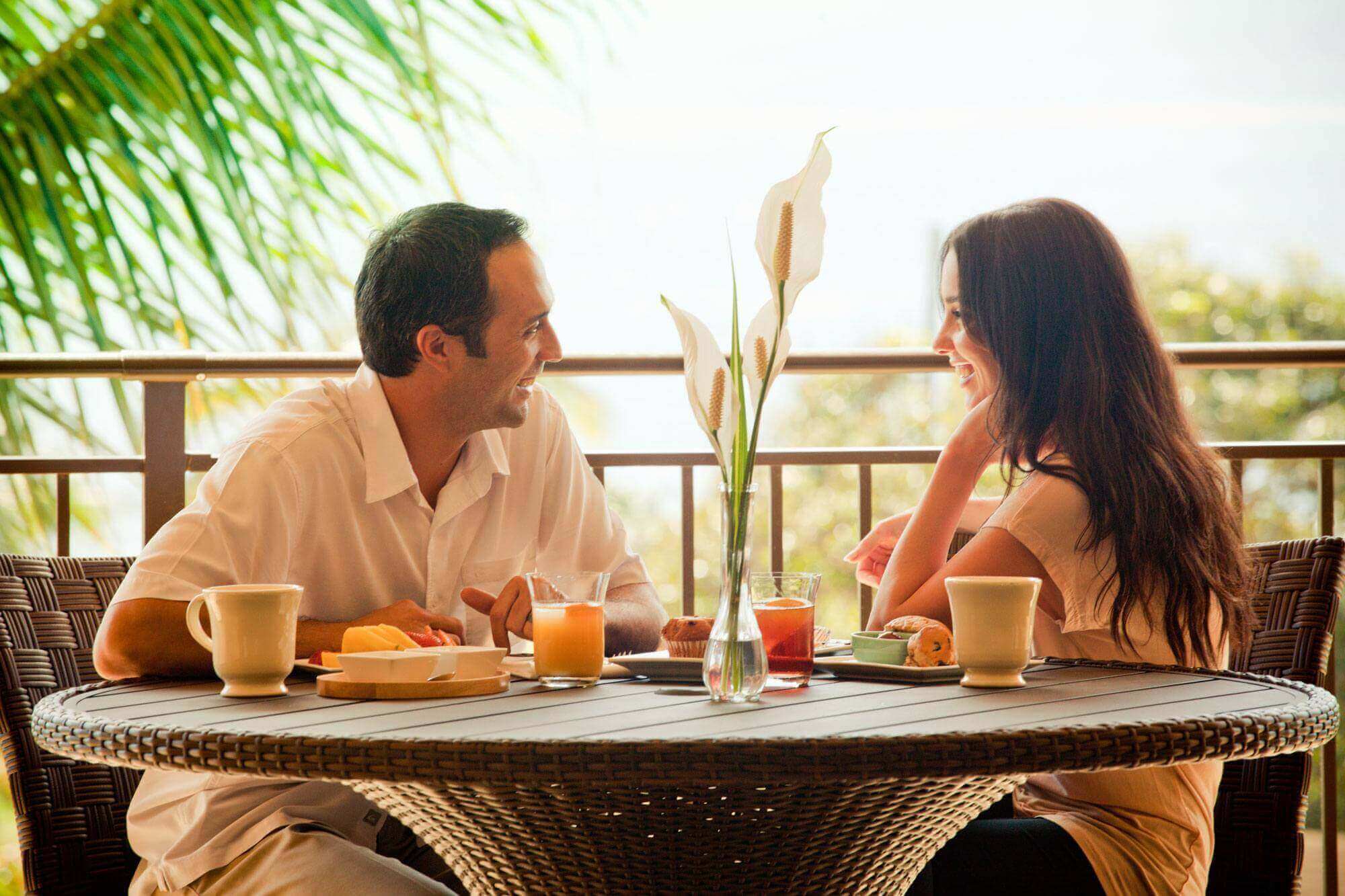 Young couple having breakfast and Kauai Juice at a beach house restaurant.