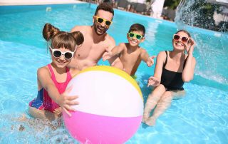 Family playing with a beach ball in the pool is ready for new family swimming pool games.