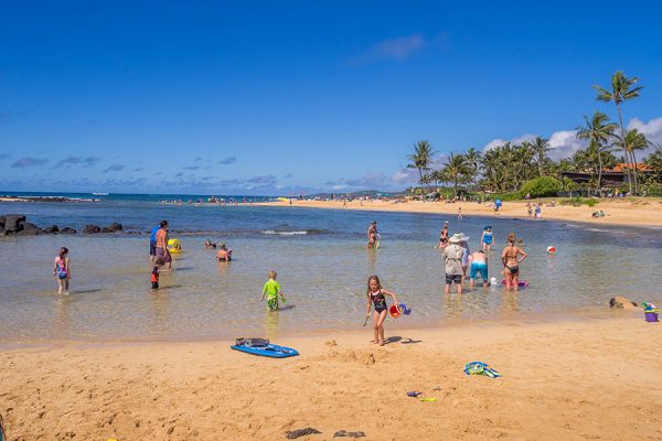 Tourists and locals enjoying Poipu Beach in South Shore Kauai
