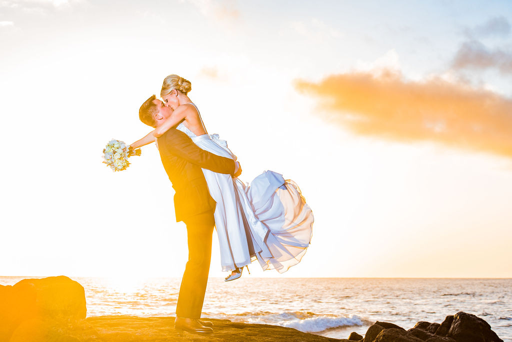 Bride being lifted by groom while they are next to the beach for the majestic photoshoot.