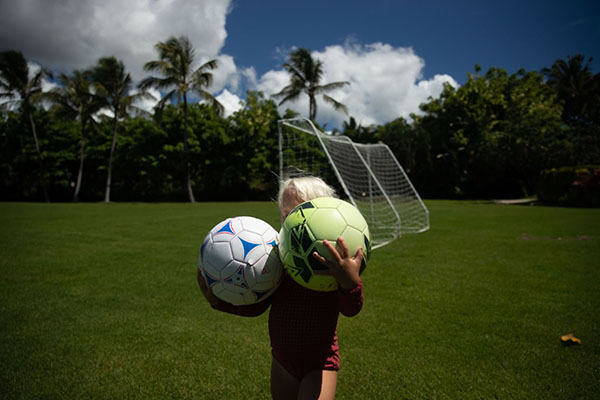 A kid playing soccer in the field.