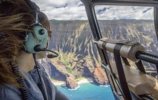 Young lady enjoying the view of napali coast during her helicopter trip in Kauai